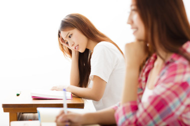 沮喪的女學生在教室里的 studiyng
