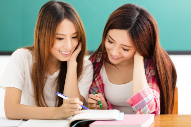 快樂(lè)的青少年學(xué)生女孩看著教室里的書(shū)