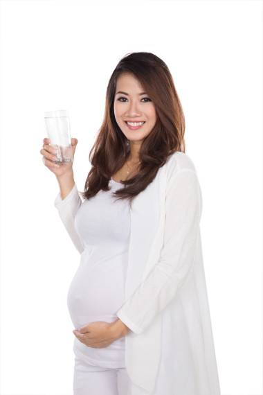 美麗的亞洲孕婦拿著一杯水微笑