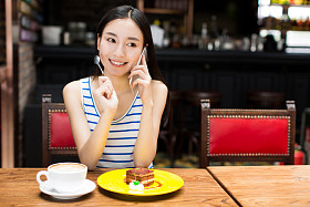 美丽的年轻女子坐在和吃蛋糕图片