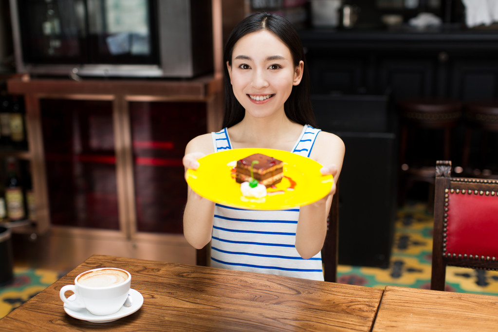 年轻美丽的女人在吃甜点