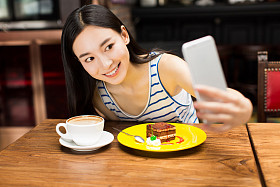 在咖啡馆店发短信在手机上的女孩
