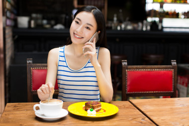 美麗的年輕女子坐在和吃蛋糕