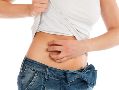 年轻女子过敏刮伤她腹部的肚子，用手指