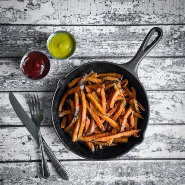 铸铁煎锅木背景上的地瓜薯条