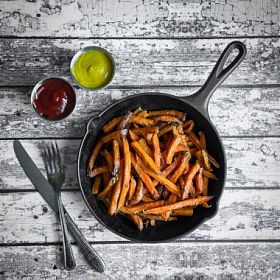 铸铁煎锅木背景上的地瓜薯条