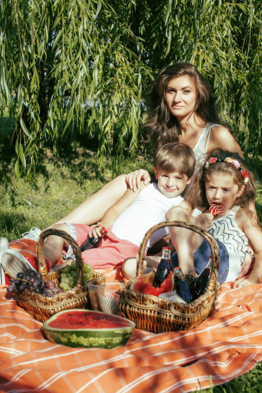 可爱的幸福的家庭野餐铺上绿草的母亲和孩子，温暖的夏季假期关闭