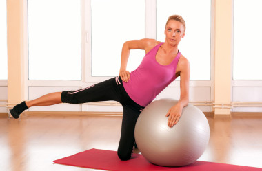 年輕女子在運動服，做健身運動與健身球