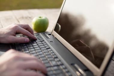 人在戶外的筆記本電腦鍵盤上打字的特寫