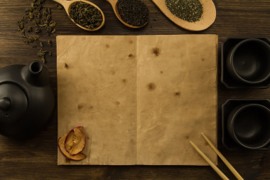 黑茶壺, 兩杯, 茶收藏, 鮮花, 木制背景上的舊空白打開書。菜單, 食譜, 模擬