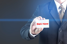 一个商人举着一块白色牌子，上面写着“现售”