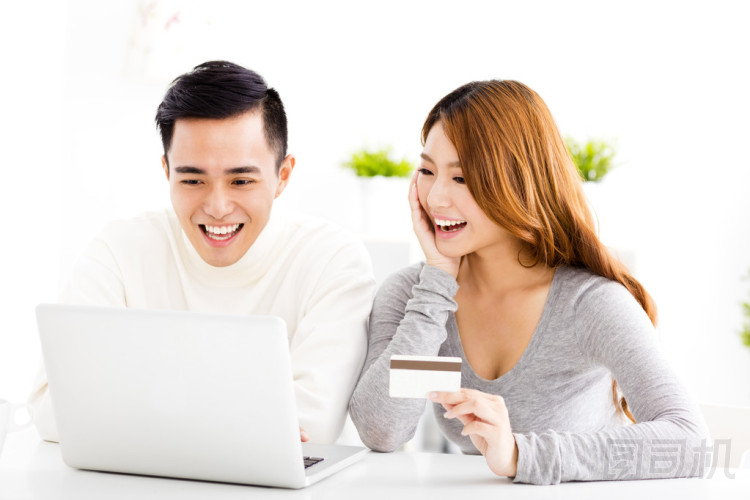 信用卡與筆記本電腦的快樂(lè)年輕夫婦