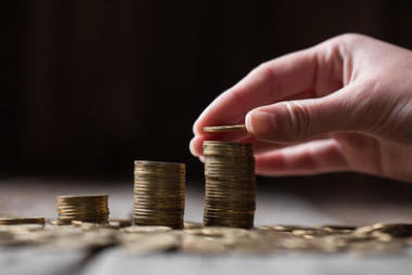 手把硬幣到堆棧上木制的背景