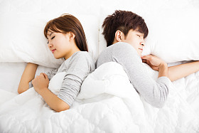 快乐年轻可爱夫妇睡在床上照片