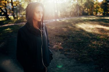 運(yùn)動(dòng)型女人戴帽夾克和聽(tīng)音樂(lè)