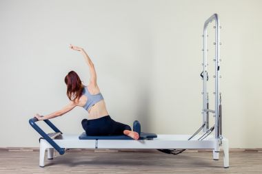 普拉提的改革者鍛煉鍛煉女人黑發(fā)在健身房室內