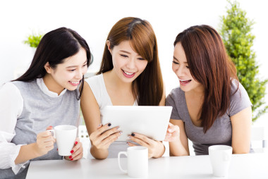 三個快樂的年輕女子看在客廳里的平板電腦