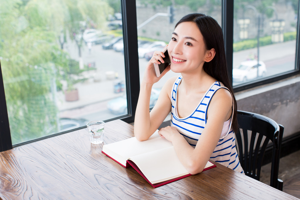 书和移动电话的女人图片