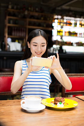 在咖啡馆店发短信在手机上的女孩