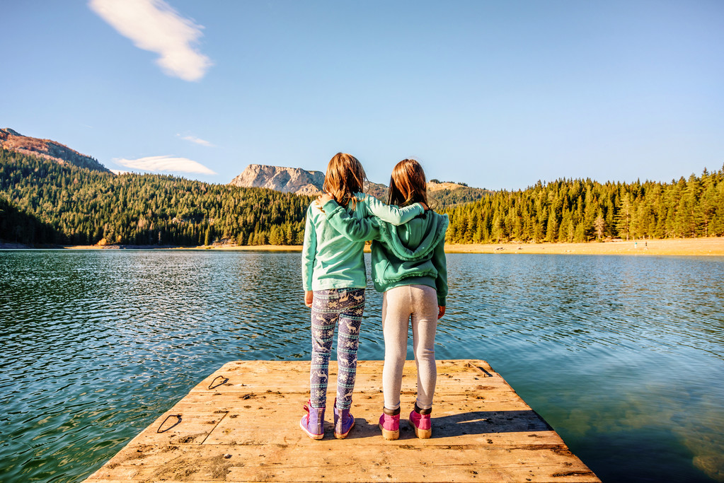 两个女朋友拥抱和 admireing 黑湖在杜尔米托尔 两个女朋友拥抱和 admireing 黑湖在杜尔米托尔