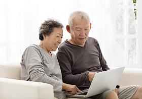 快乐高级夫妇使用笔记本电脑在沙发上