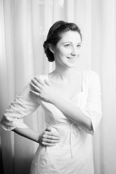 在仿空間薄紗窗簾背景上身著白色連衣裙的優(yōu)雅美麗年輕女士快樂微笑和抬頭的照片