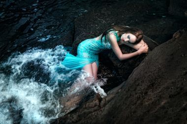 在與巖石的海灘上擺姿勢的女人