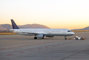 拖輪推拖拉機(jī)在機(jī)場(chǎng)跑道上的飛機(jī)