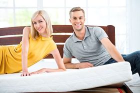 年轻夫妇坐在白色的床上