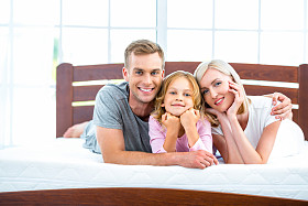 白色的床上躺着的年轻家庭图片