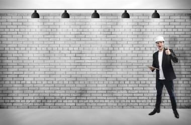 一位年轻英俊的男人建筑师与吸顶灯白色砖墙上