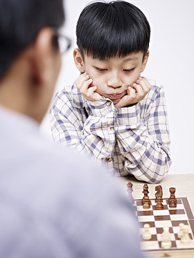 亚洲的父亲和儿子下棋照片