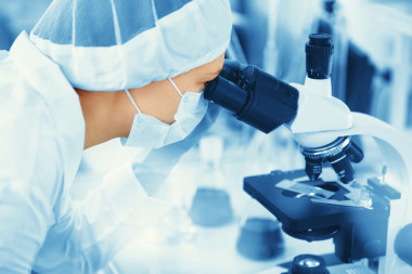 年轻的女医学研究员正在生命科学(法医微生物学生物化学)中查看显微镜幻灯片