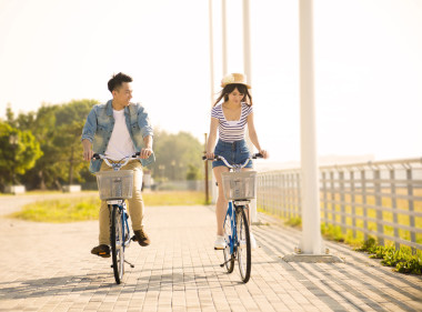 快樂的年輕夫婦，騎著自行車在城市公園