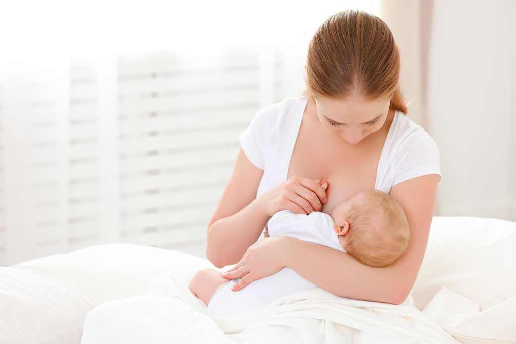 母亲母乳喂养刚出生的婴儿躺在白色的床上 母亲母乳喂养刚出生的婴儿躺在白色的床上