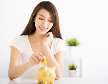幸福的年轻女人在储钱罐中插入硬