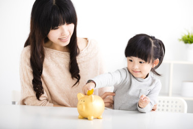 幸福的母親和女兒在儲(chǔ)錢(qián)罐中插入硬