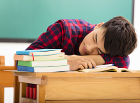 男学生在教室里桌子上睡着图片