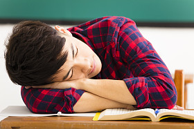 男学生在教室里桌子上睡