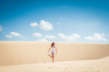 年轻女子在沙丘上运行图片