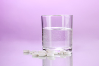 杯水和丸对紫色背景