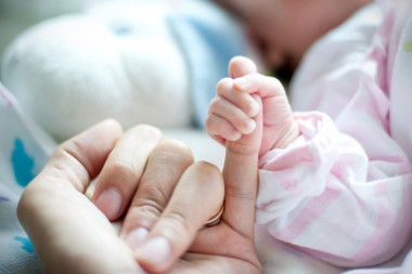 媽媽的手抱著嬰兒。照片攝于新生兒婦科