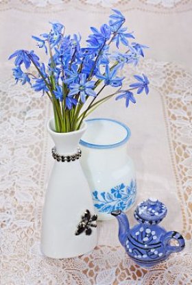 bluebel、 花瓶、 茶壶在蕾丝桌布上，生活依然