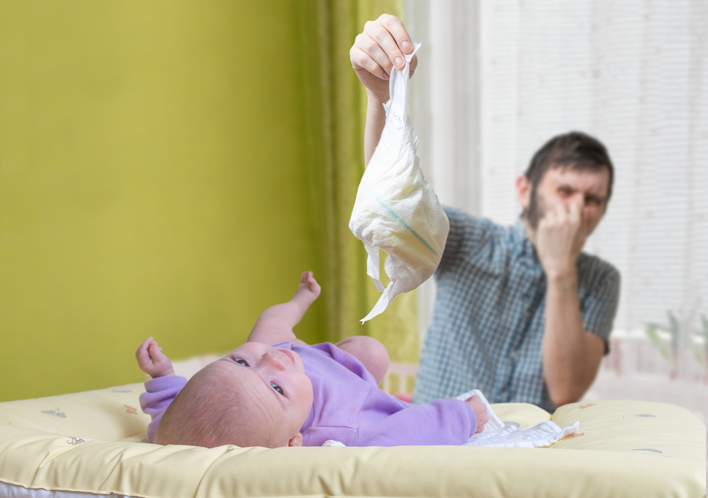 父亲改变臭尿布。婴儿腹泻的护理