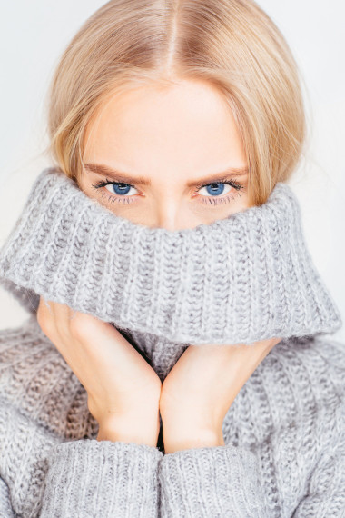 那女孩穿著毛衣和控股的手領(lǐng)上的白色背景特寫