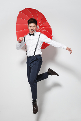 青年男人拿着红雨伞跳跃图片