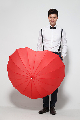 青年男人拿着心形红雨伞