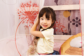 可爱的小女孩在床上玩耍照片