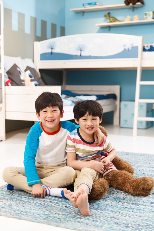 两个男孩坐在卧室的地毯上 两个男孩坐在卧室的地毯上