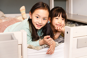 可爱的小女孩在床上玩耍照片